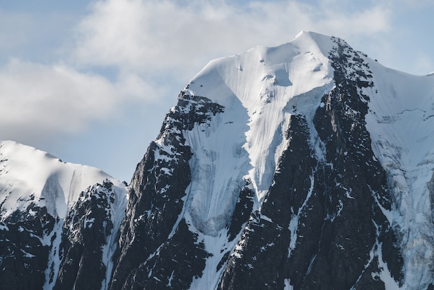 Paisaje alpino minimalista atmosférico con un enorme glaciar colgante en el pico de la montaña nevada. Gran balcón serac en el borde glacial. Cielo nublado sobre montañas nevadas. Majestuoso paisaje a gran altitud.