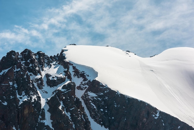 Paisaje alpino minimalista con cima de montaña cubierta de nieve y rocas afiladas a la luz del sol Minimalismo simple con montaña nevada en el cielo azul Vista mínima al pico de la montaña nevada a gran altura