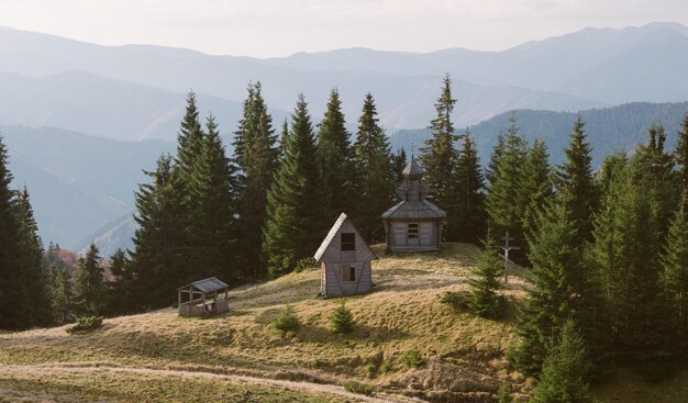 Paisaje con la antigua iglesia de madera. Bosque de montaña en un día soleado. Otoño. Cárpatos, Ucrania, Europa