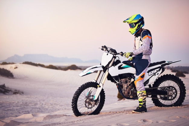 Paisaje de arena cruzada en moto o parada de hombre en bicicleta para hacer ejercicio deportivo al atardecer o hacer ejercicio en la colina Cielo natural o hombre en aventura de libertad en motocicleta en el desierto de Dubái para entrenar fitness o correr