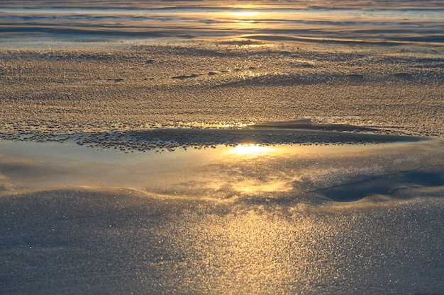 Paisaje ártico en invierno. Pequeño río con hielo en la tundra. Atardecer.