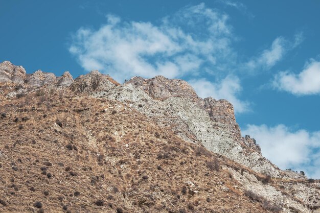 Paisaje atmosférico minimalista con pared de montaña rocosa rosa con punta puntiaguda en luz soleada. Ladera de montaña de piedra suelta en primer plano. Montañas pedregosas afiladas.