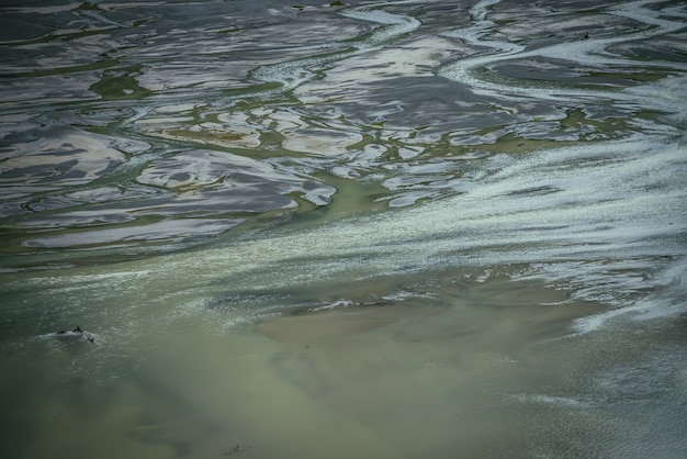 Paisaje atmosférico con muchos canales cerca del lago poco profundo. Fondo mínimo de agua verde oscuro en cardumen de lago de montaña. Fondo de naturaleza sombría de la superficie del agua verde profundo y muchas corrientes de agua.