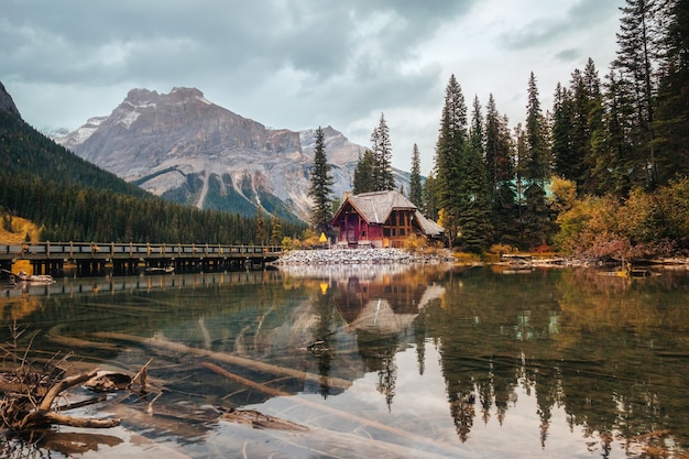 El paisaje de la casa de madera con montañas rocosas y nublado reflejo que sopla sobre el lago Esmeralda en el parque nacional Yoho, Canadá