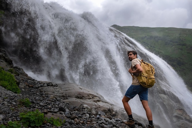 Paisaje de cascada y viajero masculino disfrutando de la vista de la cascada