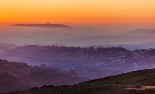 Paisaje con el cielo del atardecer sobre capas de montañas brumosas