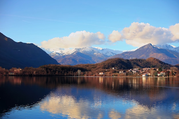 Paisaje de la ciudad de Avigliana con reflejo del cielo y las montañas en el lago tranquilo