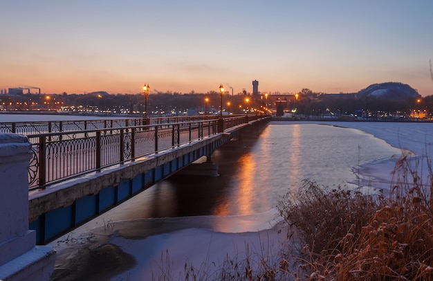 Paisaje de la ciudad del puente en la noche de invierno cubierto de nieve