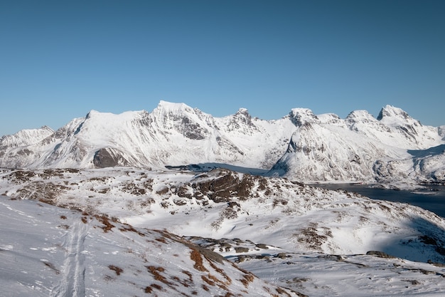 Paisaje de cordillera cubierto de nieve con cielo azul en un día soleado en las islas Lofoten, Noruega