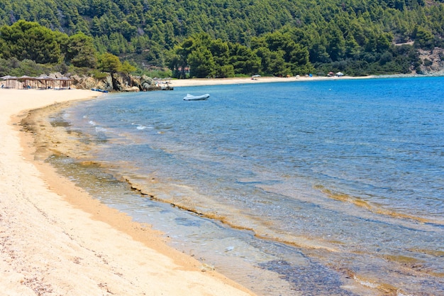 Paisaje de la costa del mar Egeo de verano con playa de arena (Sithonia, Halkidiki, Grecia). La gente es irreconocible.