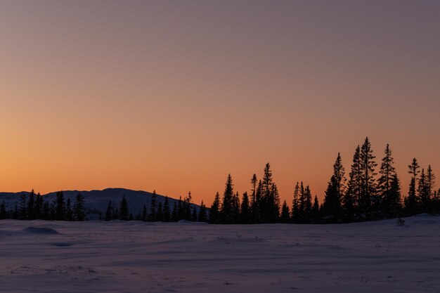 Paisaje cubierto de nieve contra el cielo durante la puesta de sol