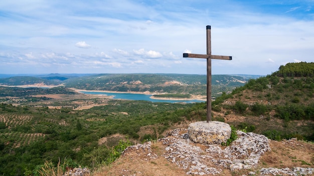 paisaje con cultivos y un pantano, en primer plano una cruz cristiana.