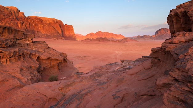 Paisaje desértico de Wadi Rum en Jordania con montañas y dunas al amanecer.