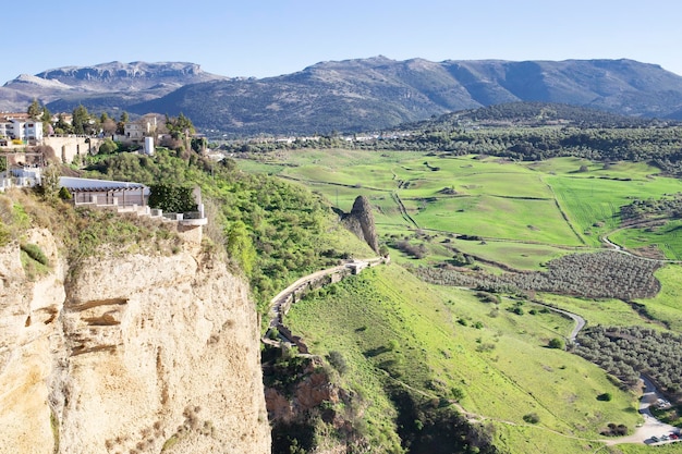 Paisaje de edificios antiguos y jardines en los acantilados de un desfiladero con un fondo de campo con huerto