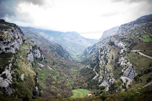 Paisaje de enormes montañas rocosas cubiertas de vegetación verde contra el cielo nublado en el valle