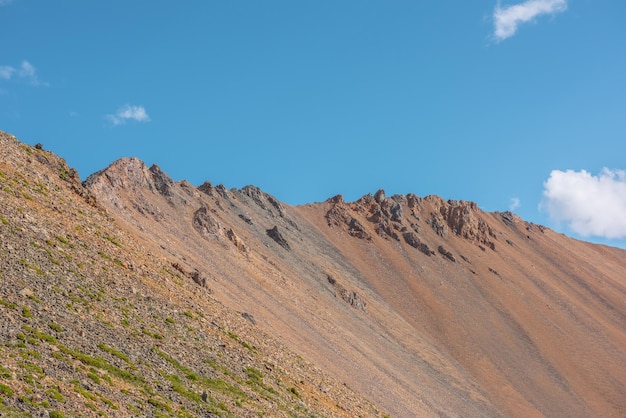 Paisaje escénico con alta cordillera rocosa iluminada por el sol bajo un cielo azul en un día soleado Paisaje colorido con una gran pared de montaña a la luz del sol Vista panorámica de las rocas afiladas en la cima de la montaña en un sol brillante