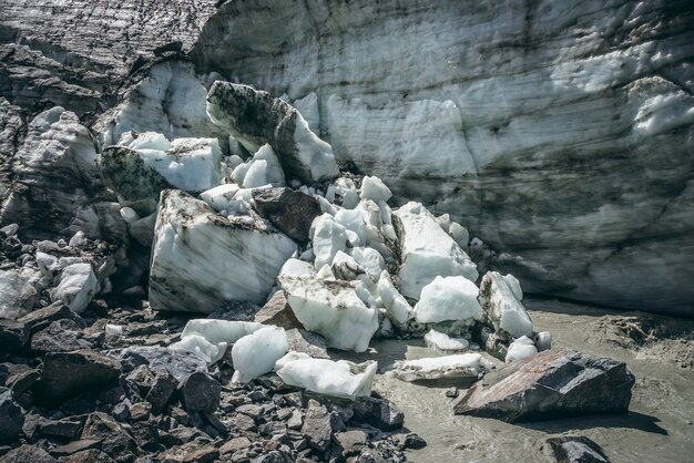 Paisaje escénico con un poderoso río de montaña que comienza desde un glaciar con trozos de hielo. Hermoso paisaje con glaciar en la fuente del turbulento río glacial. Río de montaña entre morrenas y bloques de hielo.