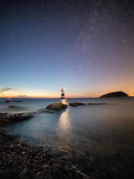 Foto el paisaje del faro en una isla costera bajo las estrellas por la noche