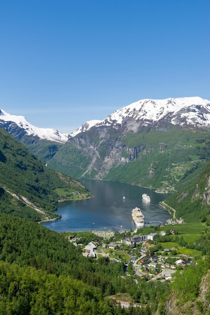 Paisaje del fiordo y el pueblo de Geiranger con altas montañas nevadas y cascadas Noruega