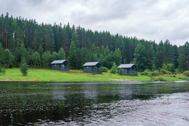 paisaje fluvial con cabañas en una orilla boscosa