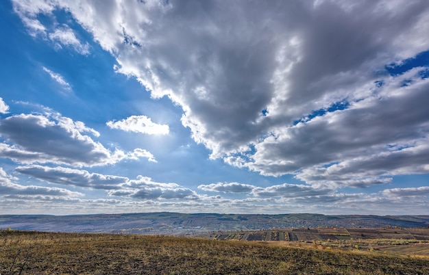 Paisaje de fondo otoñal con cielo oscuro y nubes plateadas