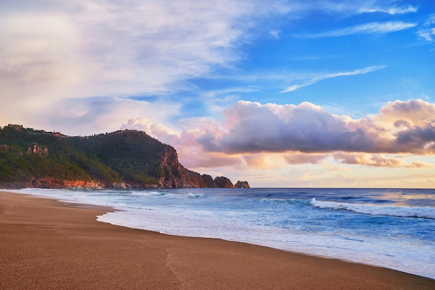 Paisaje de fondo de pantalla de cielo tranquilo idílico y pacífico con nubes esponjosas, cresta de montaña verde, costa del mar y playa de arena