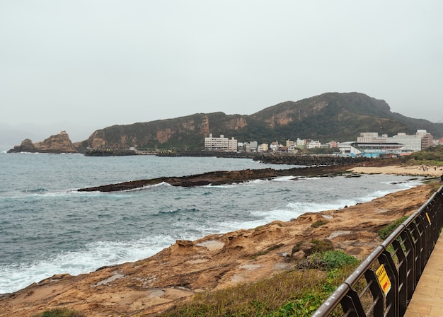 Paisaje del Geoparque Yehliu, un cabo en la costa norte de Taiwán. Un paisaje del mar con edificios de la ciudad.