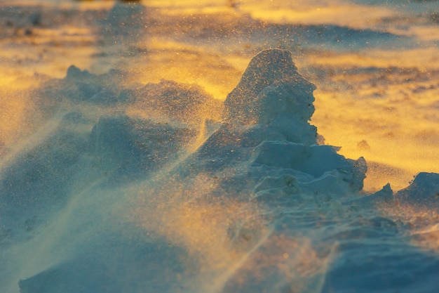 Paisaje helado ilimitado durante una tormenta de nieve en la puesta del sol en invierno.