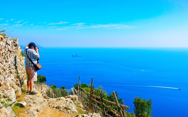 Paisaje con hombre turista caminando por el Camino de los Dioses en Italia en Nápoles. Costa y paisaje de Amalfi con el mar Tirreno en el italiano Positano. Panorama de la costa de Amalfitana en Europa. Ver en verano.