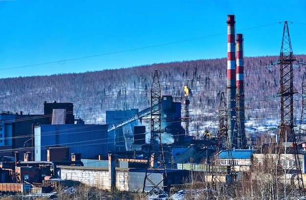 Paisaje industrial: la antorcha de una planta química de coque produce emisiones térmicas a la atmósfera en el contexto de un paisaje invernal.