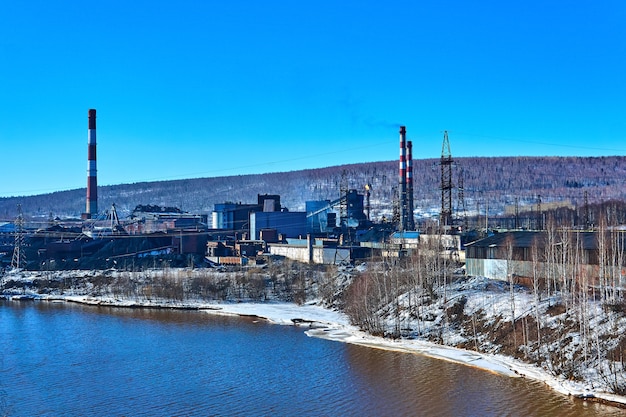 Paisaje industrial de invierno con una antigua planta de coquequímica en un valle en la orilla del río