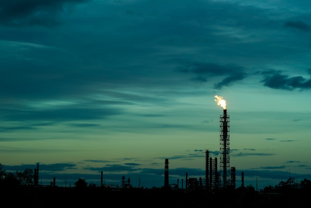 Paisaje industrial silueta nocturna - bengalas para la quema de gas asociado en un campo petrolífero