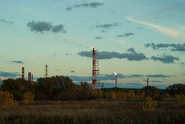 Paisaje industrial vespertino: bengalas por quema de gas asociado en un campo petrolífero