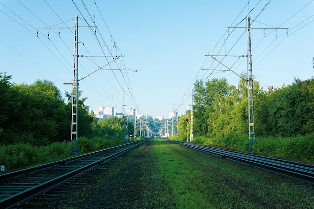 Paisaje industrial: vías férreas que conducen a la ciudad en una colina en la distancia