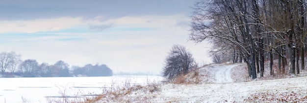 Paisaje invernal con bosque en el río y hermoso cielo en tiempo nublado