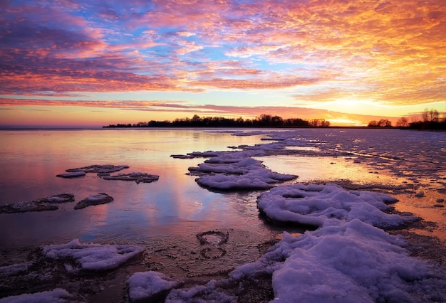 Paisaje invernal con lago y cielo ardiente al atardecer. Composición de la naturaleza.