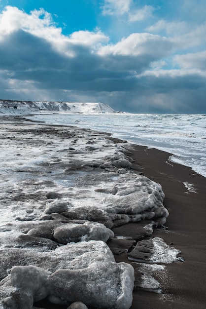 Foto paisaje invernal con mar congelado y playa helada, tormenta y clima nevado espectacular paisaje marino