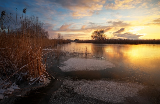 Paisaje de invierno con cielo al atardecer y río congelado. Alba