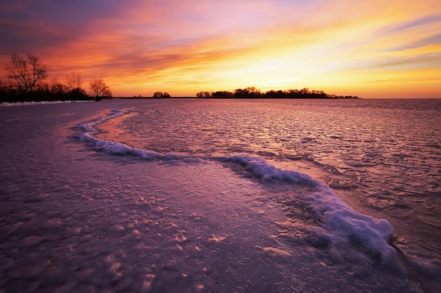 Paisaje de invierno con cielo ardiente al atardecer.