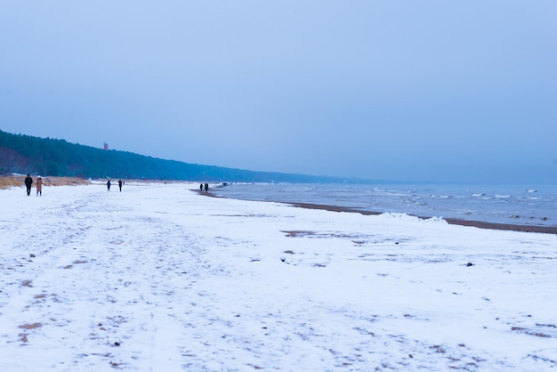 Paisaje de invierno, gente caminando en la playa del mar de invierno