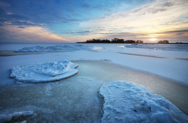 Paisaje de invierno con lago congelado y cielo al atardecer. Composición de la naturaleza.
