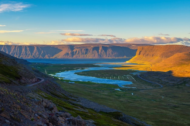 Paisaje islandés con fiordo y camino de ripio al atardecer en los fiordos del oeste de islandia