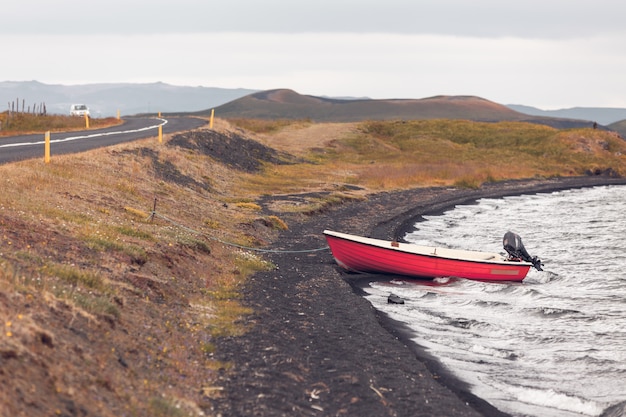 Paisaje de Islandia con un barco rojo en la costa