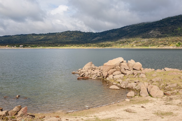 Paisaje de un lago con un primer plano de rocas de granito amontonadas en la orilla