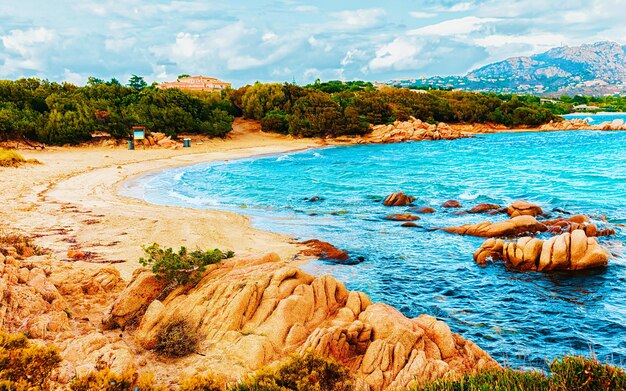 Paisaje con mañana romántica en la playa de Capriccioli en Costa Smeralda del mar Mediterráneo en la isla de Cerdeña en Italia. Cielo con nubes. Porto Cervo y provincia de Olbia. Técnica mixta.