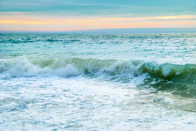 Paisaje de mar con grandes olas y puesta de sol.