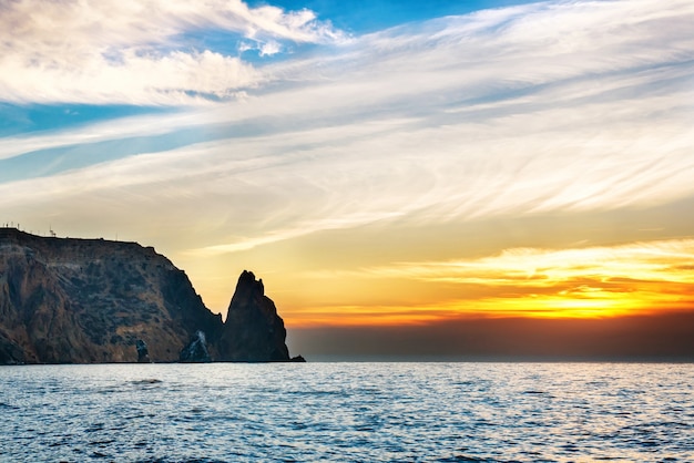 Paisaje de mar con puesta de sol sobre rocas y cielo espectacular