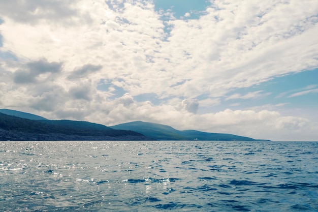 Paisaje de mar, superficie del agua, cielo nublado y montañas