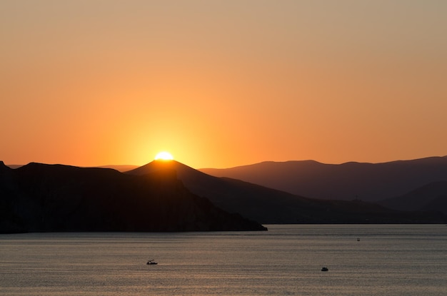 Paisaje de mar de verano. Vista de las montañas y el sol poniente