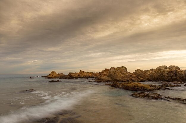 Paisaje marino al atardecer con rocas y olas